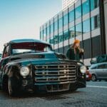 Czarny zabytkowy samochód zaparkowany przy miejskim chodniku