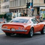 Czerwony zabytkowy Pontiac jedzie ruchliwą ulicą miasta