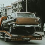 Klasyczne auto na lawecie na miejskiej ulicy między nowoczesnymi budynkami