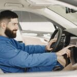 Mechanik w niebieskim kombinezonie sprawdza deskę rozdzielczą klasycznego auta
