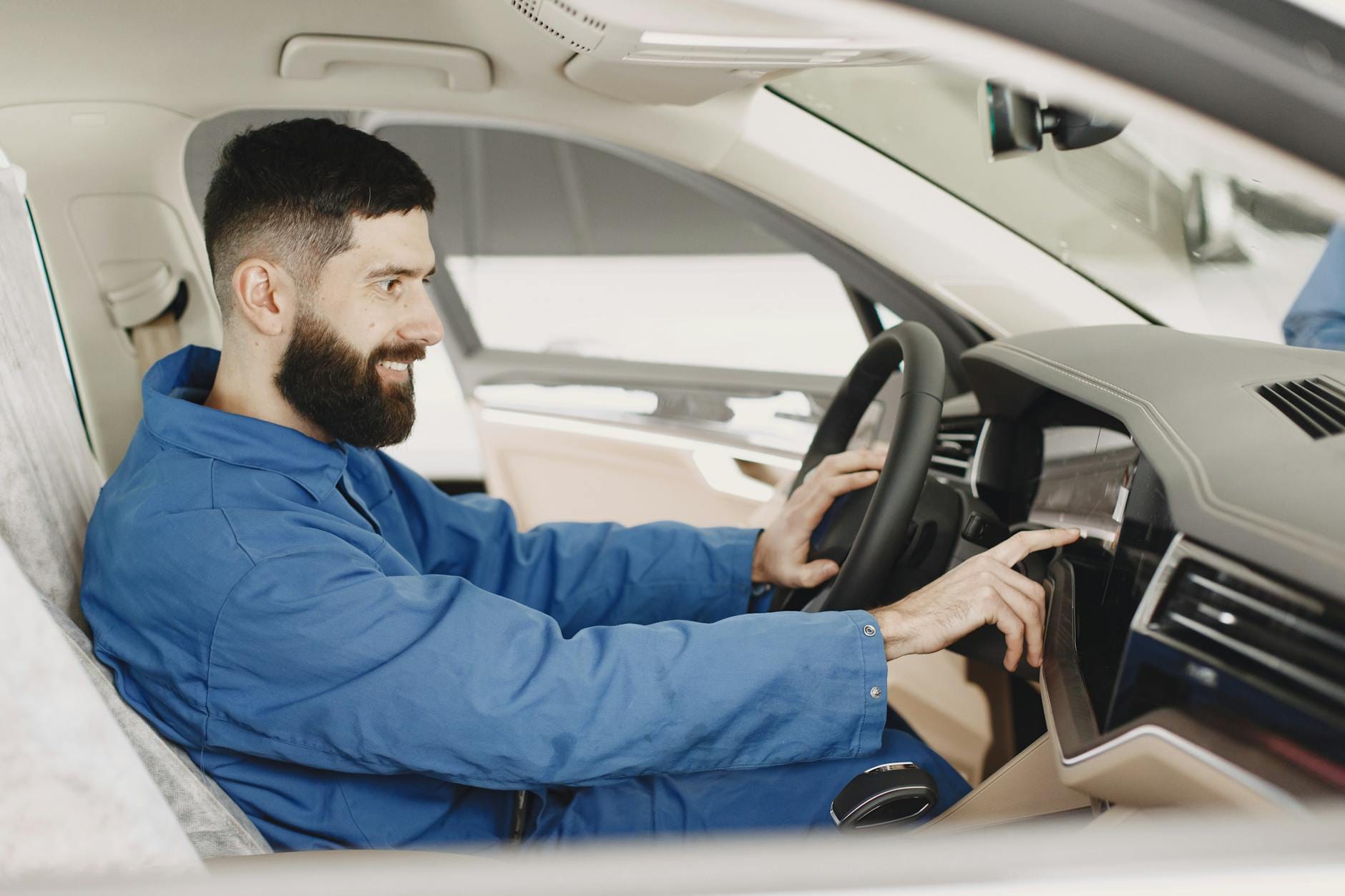 Mechanik w niebieskim kombinezonie sprawdza deskę rozdzielczą klasycznego auta