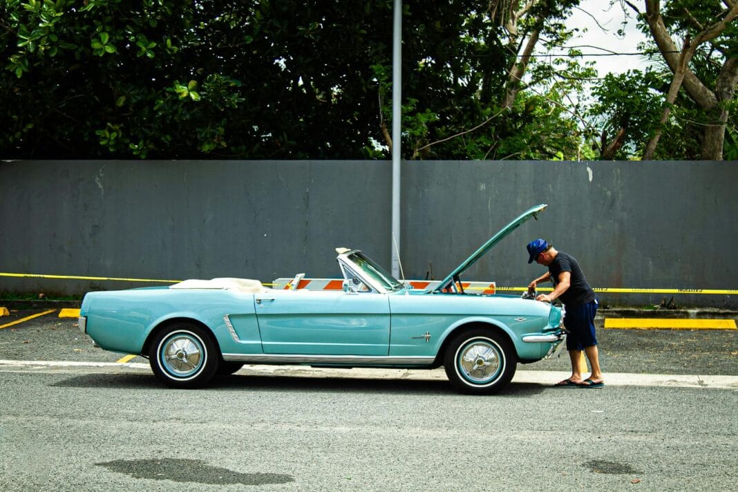 Mężczyzna sprawdza niebieskie retro cabrio przed długą trasą