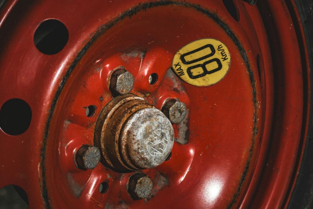 Zardzewiałe czerwone koło zapasowe z napisem 80 km/h maksymalnej prędkości