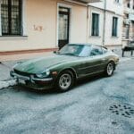 Zielony klasyczny Datsun zaparkowany przy ulicy w zabudowie miejskiej