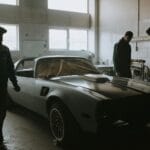 Mechanicy odnawiają klasyczne auto w półmrocznym garażu