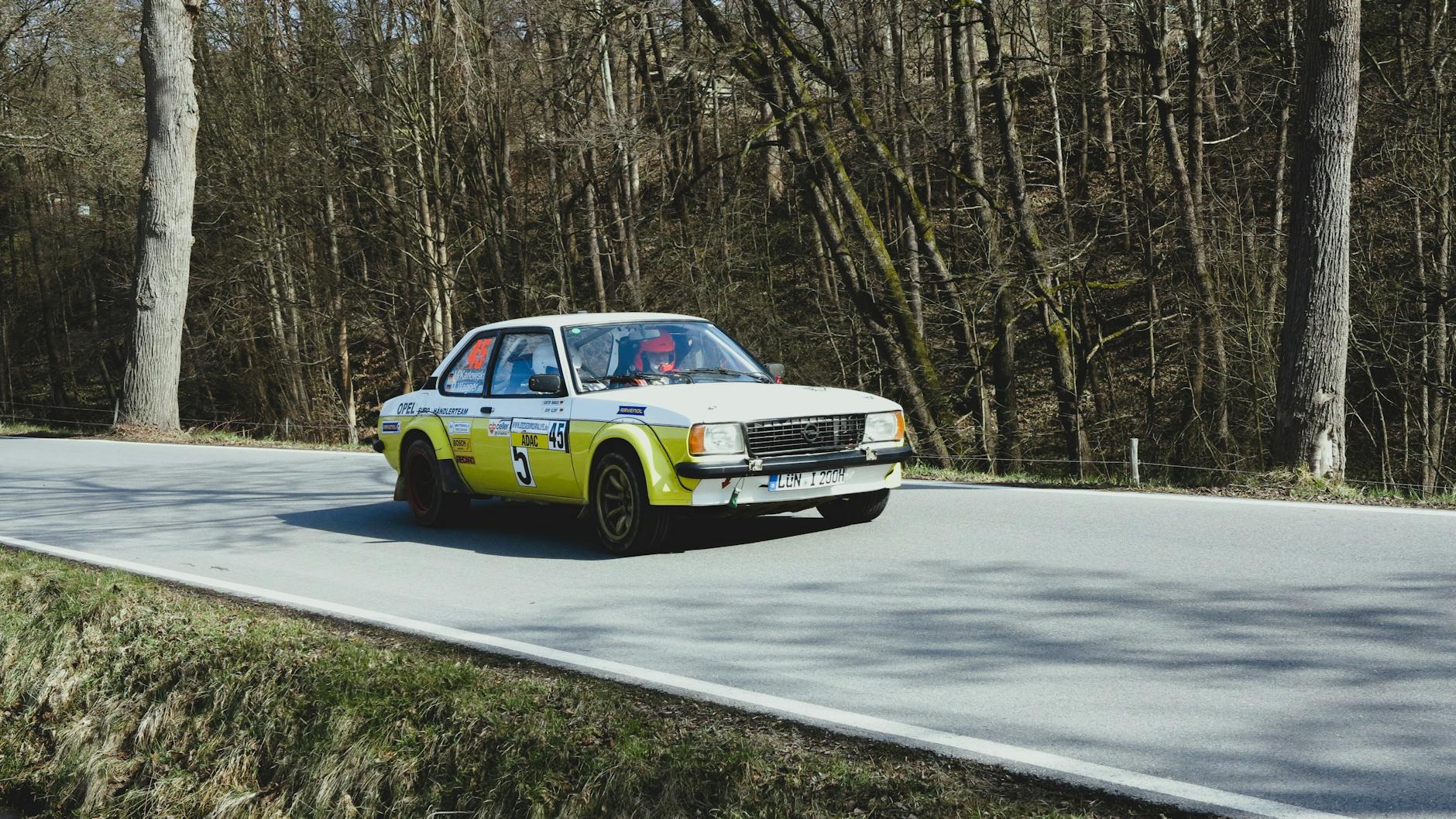 Rajdowa Lancia Delta Integrale pędzi leśną drogą w słońcu