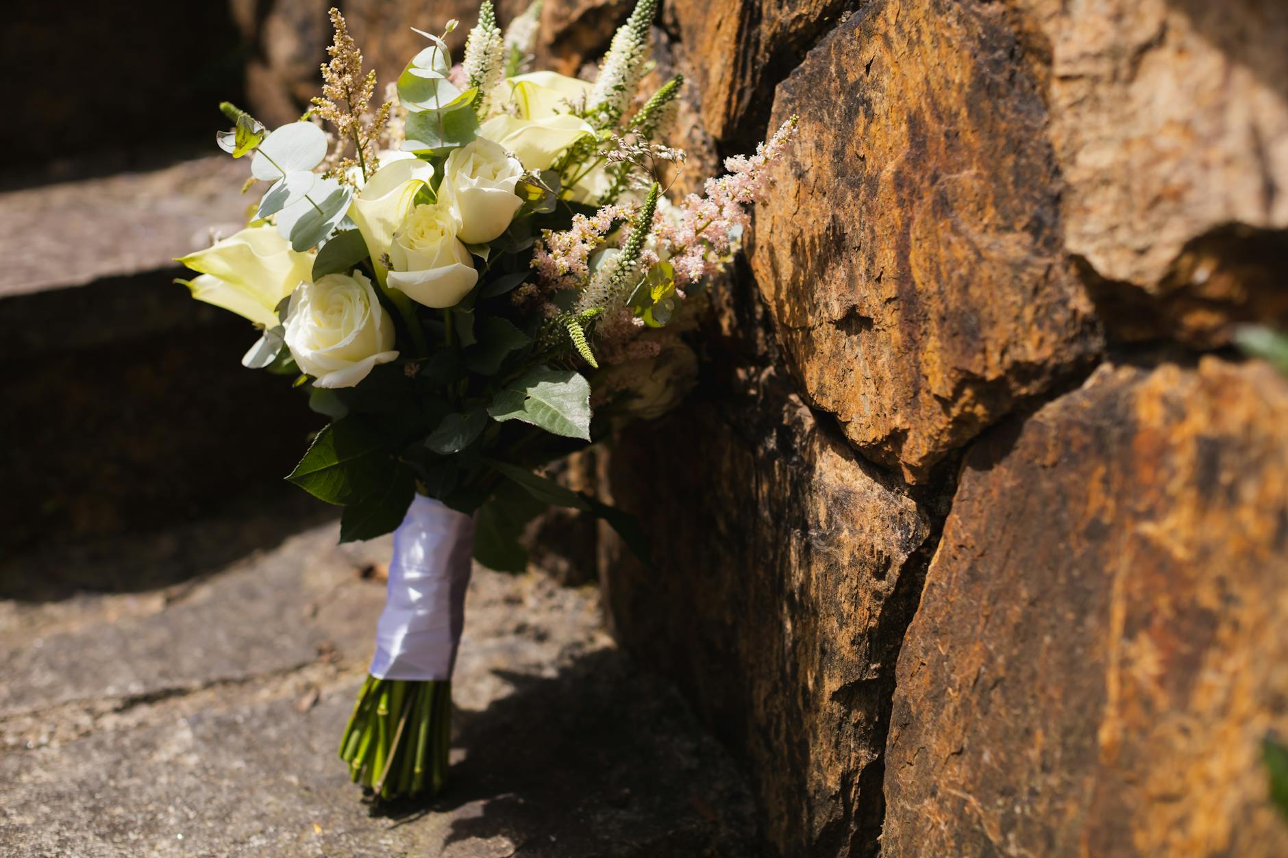 Rustykalny bukiet ślubny oparty o kamienny mur
