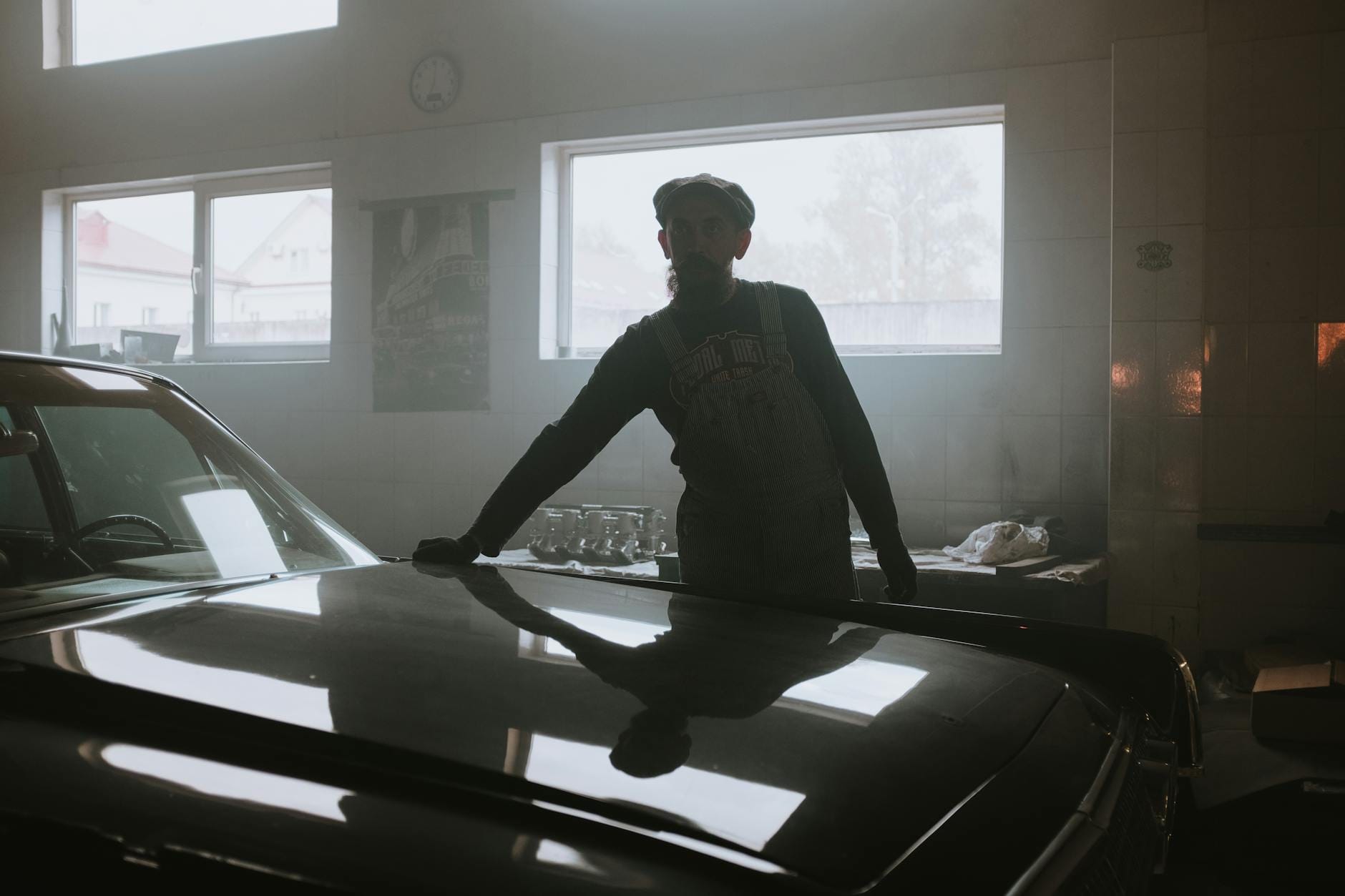 Sylwetka mechanika przy zabytkowym aucie w ciemnym garażu